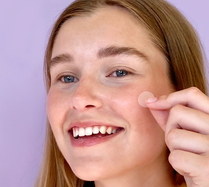 Girl smiling holding up pimple patch to her face